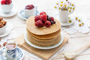 Raw vegan pancakes on a wooden plate with raspberries on top. Healthy eating lifestyle.