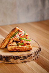 Presentable plating of Belgian waffle topped with chicken and sauce on a nice cut wooden chopping board. Food photography concept for magazine or online delivery menu.