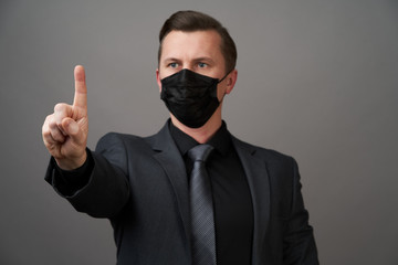 Businessman with surgical medical mask pointing with finger.