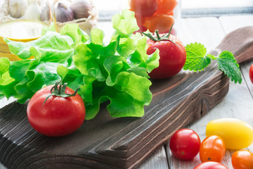 red tomato and salad vegetables on cutting board rustic style close-up