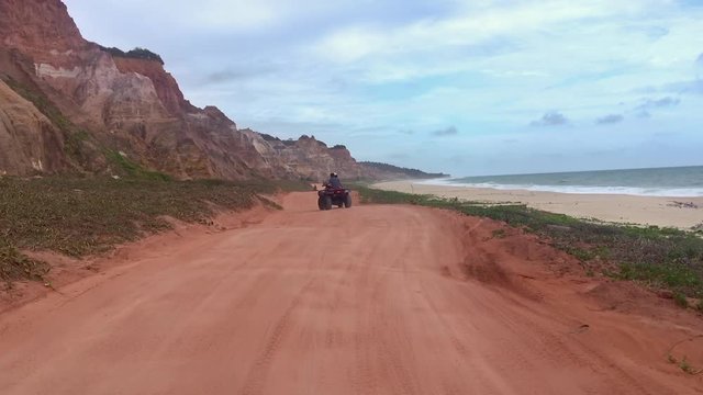 Tourists by the cliffs bordering the sea near Gunga beach in Alagoas, Brazil