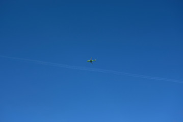 green plane flies high in the blue sky