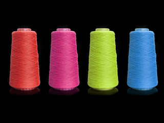 Yarn for knitting on bobbins, bobbin yarn on a black background. Knitting, machine knitting.