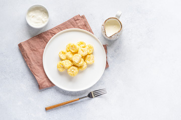  Curd and cheese dumplings served with berries and sour cream on a ceramic white plate. Traditional Ukrainian or Russian lazy dumplings (vareniki). Healthy Breakfast, top view.