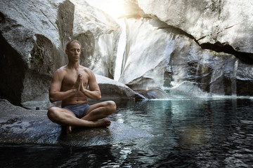 Naklejka na ściany i meble young athletic boy doing iodine and meditation in a waterfall