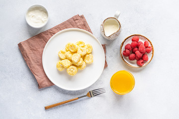 Curd and cheese dumplings served with berries and sour cream on a ceramic white plate. Traditional Ukrainian or Russian lazy dumplings (vareniki). Healthy Breakfast, top view.