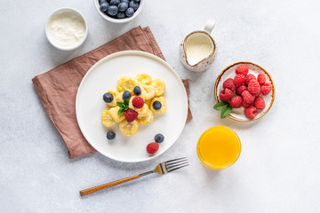  Curd and cheese dumplings served with berries and sour cream on a ceramic white plate. Traditional Ukrainian or Russian lazy dumplings (vareniki). Healthy Breakfast, top view.