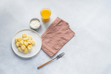  Curd and cheese dumplings served with berries and sour cream on a ceramic white plate. Traditional Ukrainian or Russian lazy dumplings (vareniki). Healthy Breakfast, top view.