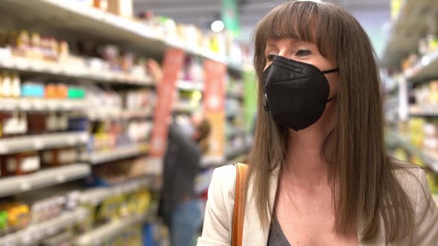 Young woman in face mask shopping in grocery store supermarket.