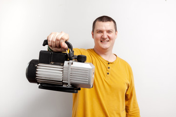 A strong man holds tvacuum pumps for refrigeration in his hands.