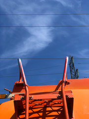 Rear view of big orange fuel tanker truck on against blue sky