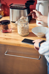 Caucasian woman keeping spoon with oatmeal in kitchen