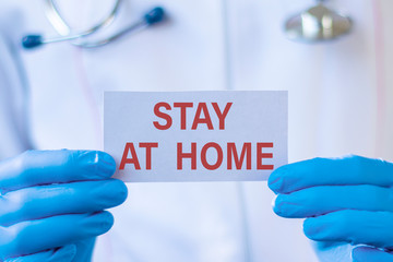 Stay at home text on card and hands holding it. Healthcare or prevention concept.