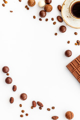 Candy background with chocolate and coffee on white desk top view frame. Cafe concept. Copy space