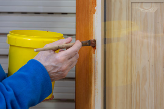 Una persona barnizando una ventana de madera