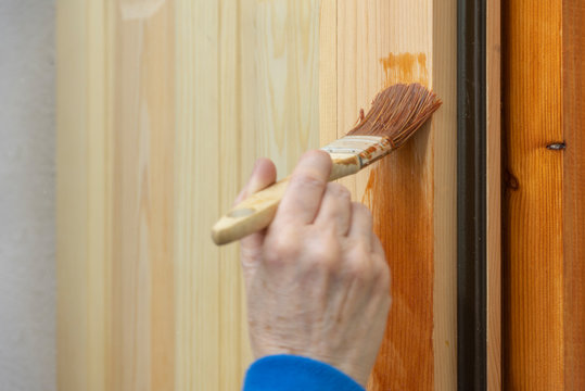 Una persona barnizando una ventana de madera