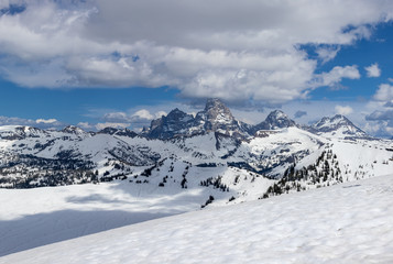 Fototapeta na wymiar Eastern view of the Grand Tetons covered in snow with clouds and blue sky