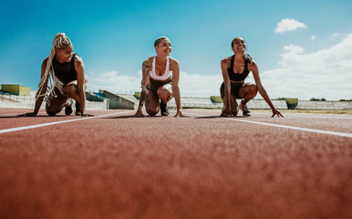 Female athletes ready to start a race on stadium track