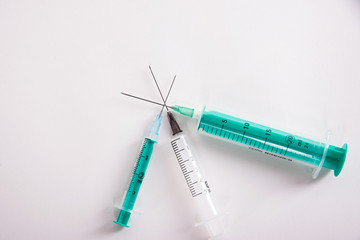 syringes are on a white background, along the edge of the frame are three syringes with needles