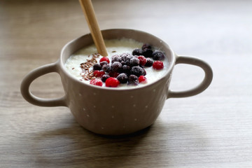 Bowl of rice porridge with seeds and frozen berries. Selective focus.