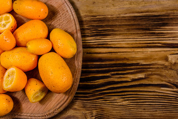 Cutting board with kumquat fruits on wooden table. Top view