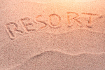 RESORT lettering on sand with wave and evening light. Minimal exotic vacation and travel concept, Flat lay top view copy space