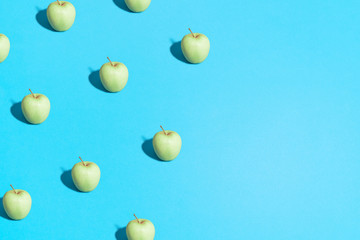 green Apple pattern on bright light blue background. Minimal flat lay food texture. Summer abstract trendy fresh concept.