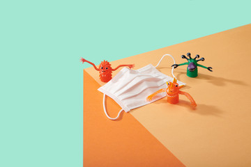 Corona Virus Covid 19 White particle face mask with germs cooties toys lined up on edge of table surface kid friendly image