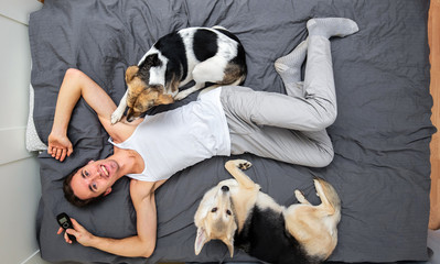 Man and dogs lying on bed with gray sheet