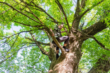 Casual guy relaxing on the tree branch in the forest