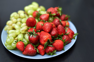 ripe strawberries and grapes on a plate