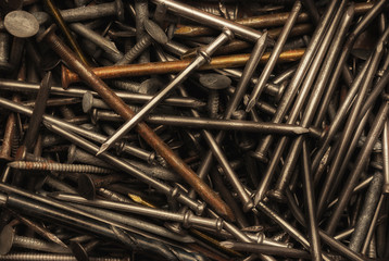 Closeup of a pile of random assorted nails rusty and shiny with strong warm side light.