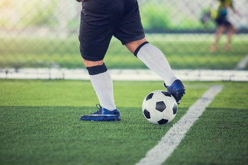 Obraz premium Soccer player control to shoot ball on green artificial turf to goal. Boy soccer player training for match. Football player in football academy.