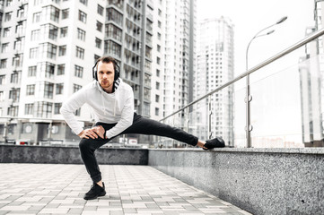 Stretching outdoors. A young man doing exercises among cityscape