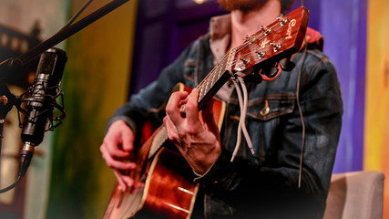 Fototapeta na wymiar Man in jeans jacket playing acoustic guitar - side