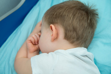 Little boy sleeps in his bed and  turns away