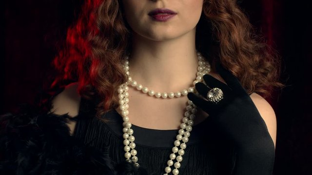 Woman dressed in style of Great Gatsby demonstrates jewelry and bijouterie of that time on hands and dress. Roaring twenties, retro fashion, vintage lady costume