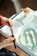 modern female putting liquid foundation on cosmetic brush