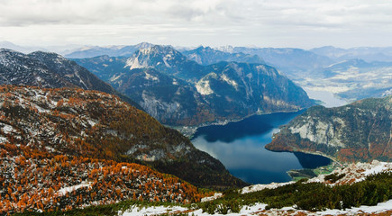 Fototapeta na wymiar View from above to Hallstatter lake and Hallstatt village among Alps mountains in Austria. Beautiful nature landscape. Autumn season and trees with orange colour. Wonderful valley and ridges.