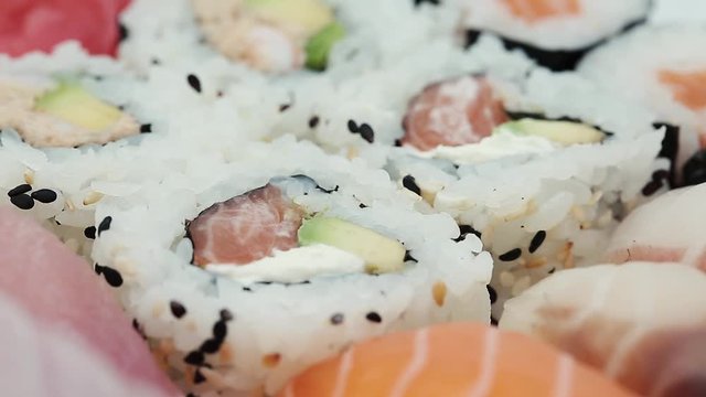 Sushi and Sashimi rolls rotating. Fresh made Sushi set with salmon, prawns, wasabi and ginger. Traditional Japanese cuisine.