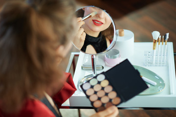 elegant female looking in mirror and using concealer palette