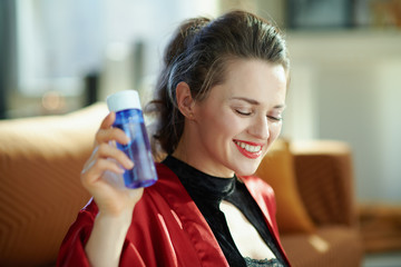 smiling woman with facial cleanser at modern home in sunny day