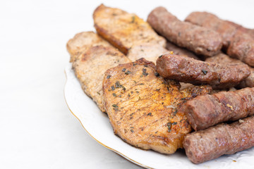 Mixed grilled meat on the plate. Grilled kebabs and pork chops served on the plate