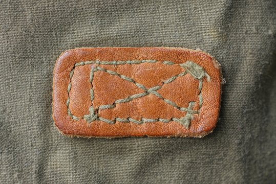 Brown Leather Patch Texture With Stitches On Green Fabric