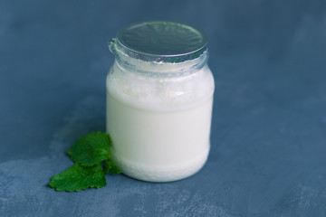 Yogurt in a glass package with mint leaves on a dark gray background. Healthy Nutrition, Essential Dairy Products