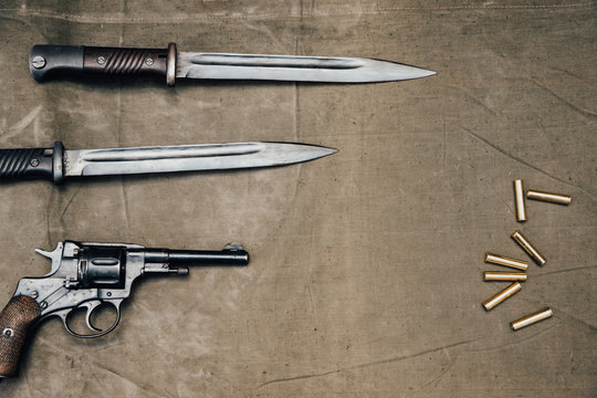 Bayonet knife with revolver Nagan system on an old surface in retro style.