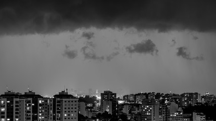 Imagens da chegada de uma tempestade de verão com raios e chuva, na cidade durante a noite em...