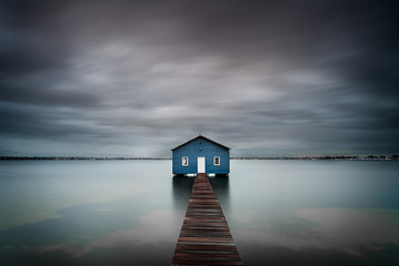 Blue boat shed on the river with cloudy sky