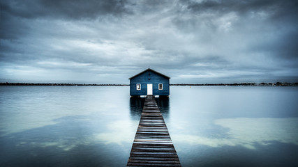Blue boat shed on the river with cloudy sky