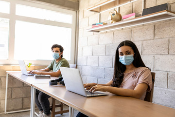 Young woman with a face mask working from home office